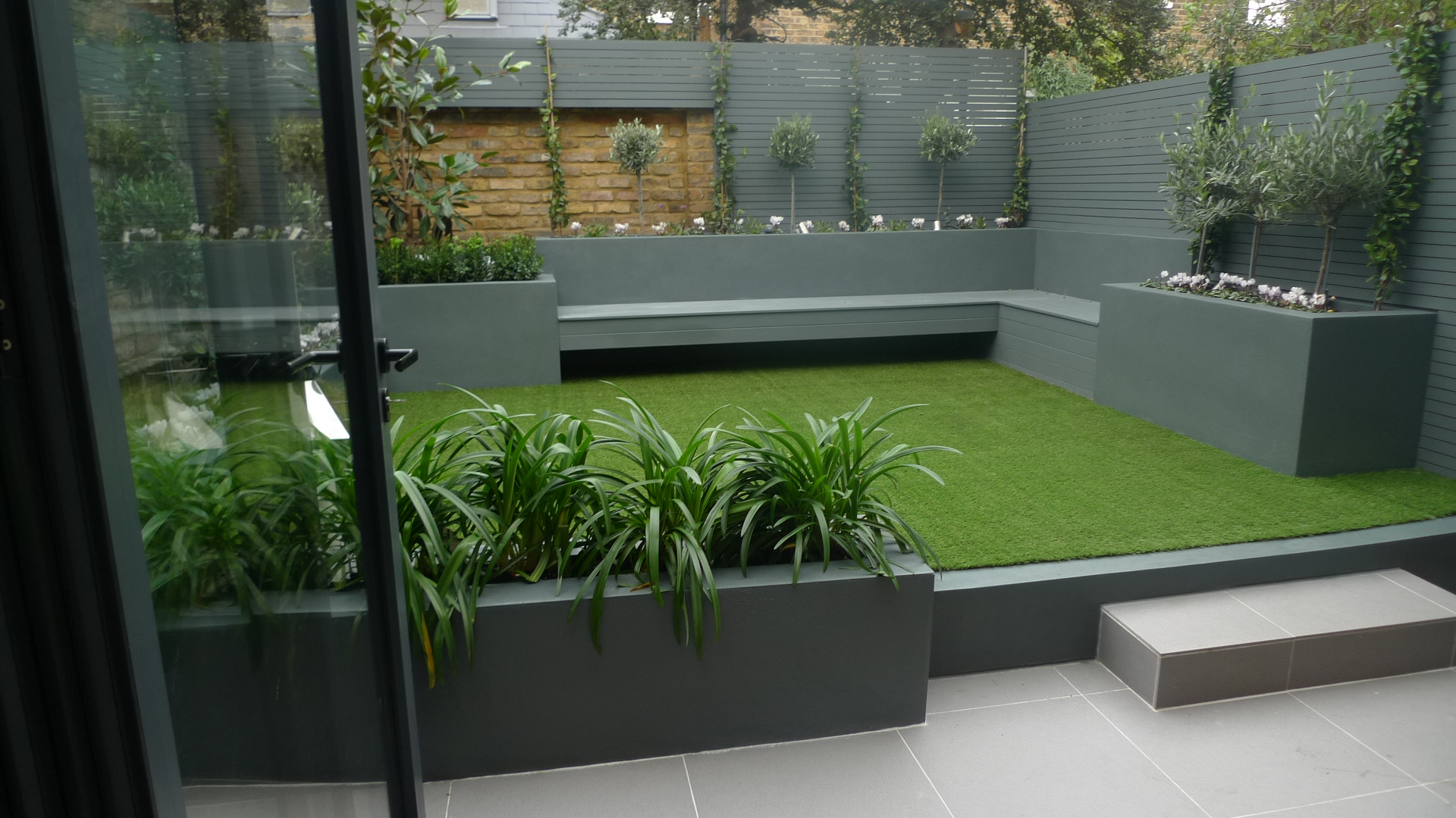 Modern small low maintenance garden fake grass grey raised beds