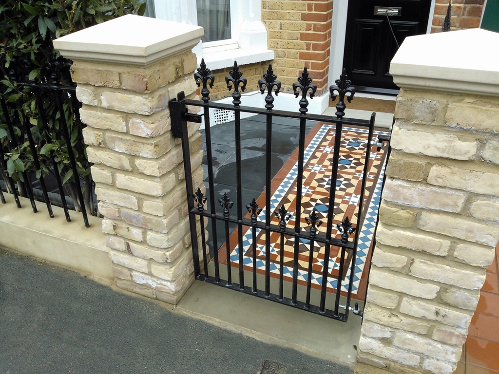 mosaic tile path with wrought iron rails yellow brick wall and slate paving london