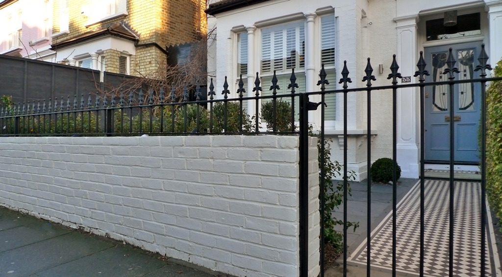 black and white mosaic tile path with white painted wall with metal rail and gate london (2)