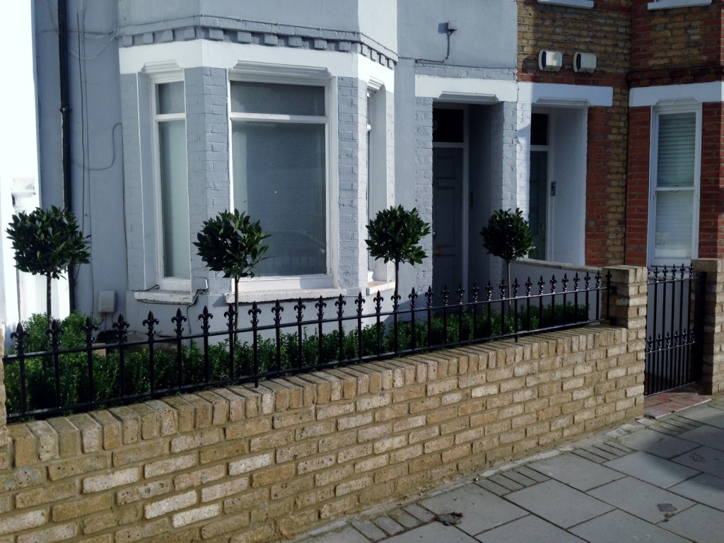 Yellow brick garden wall metal rail and gate bay and buxus topiary Clapham Battersea Balham London (2)